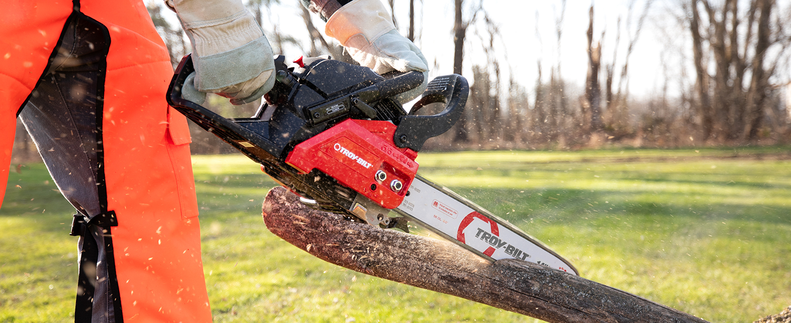 close up of person cutting a log with a chainsaw