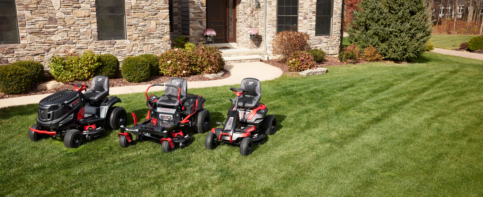 new troy-bilt electric riding mowers next to each other in front of a house