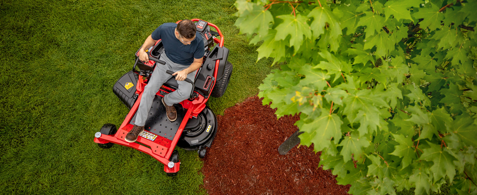 top view of man mowing around a tree with zero-turn mower