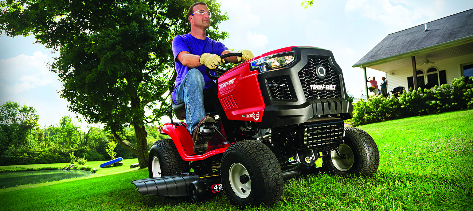 man on Troy-Bilt gas riding mower on grassy yard