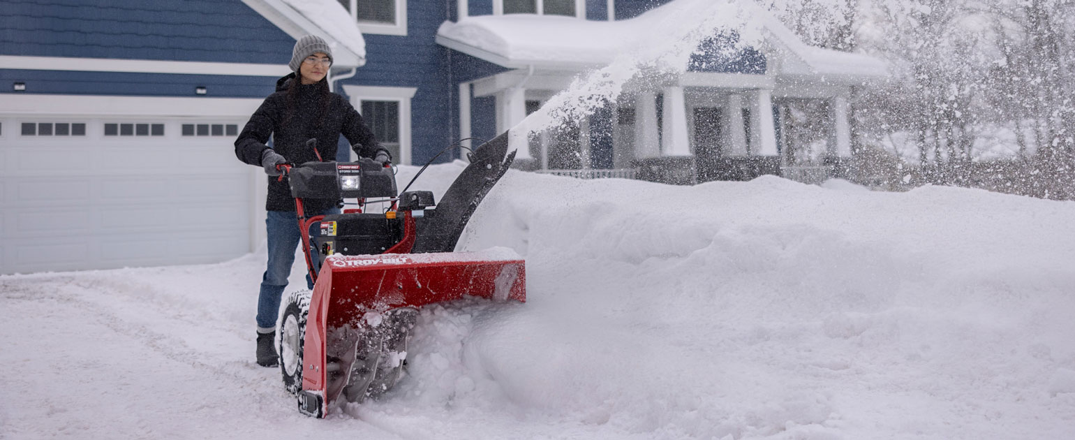 person plowing driveway with two stage snow blower