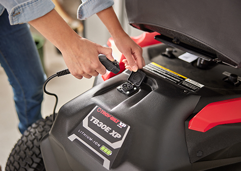 woman plugging in charger into electric mini-rider