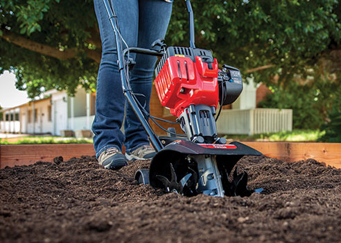 Woman cultivating garden with Troy-Bilt gas-powered cultivator