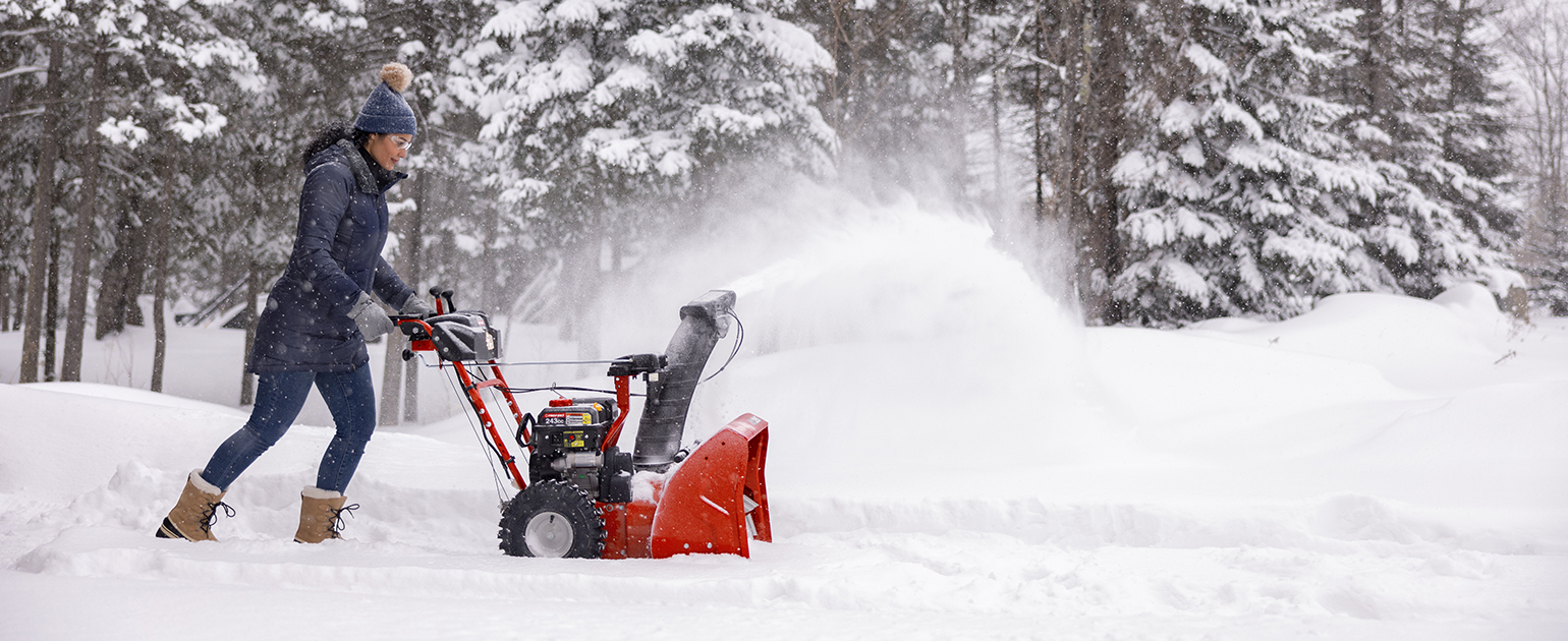woman pushing snow blower through large amounts of snow