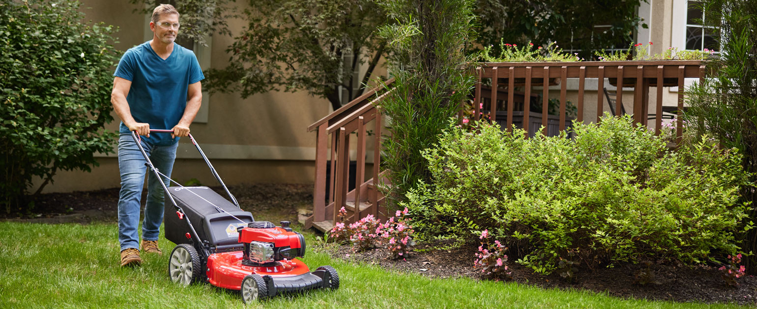 man cutting the grass with walk behind mower