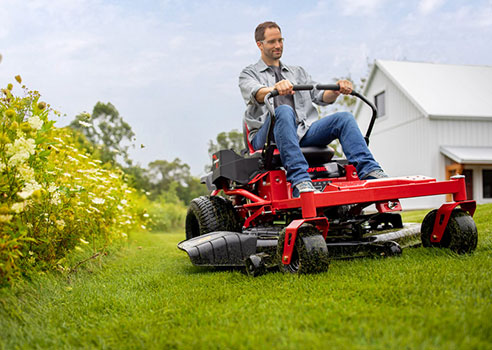 man riding top-rated troy-bilt zero-turn riding lawn mower on yard