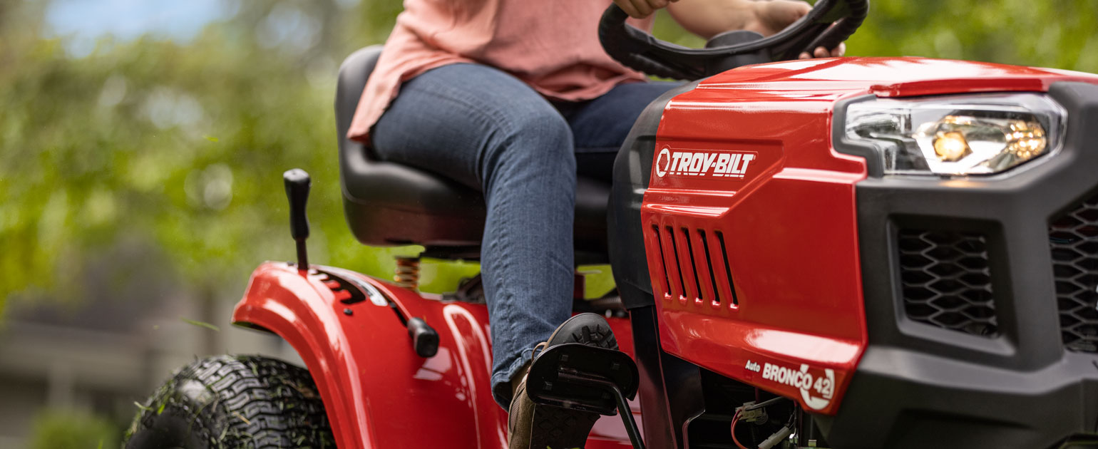 close up of woman cutting lawn with a riding mower