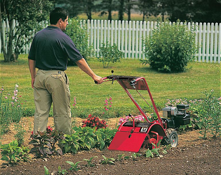 Man operating Troy-Bilt walk-behind tiller