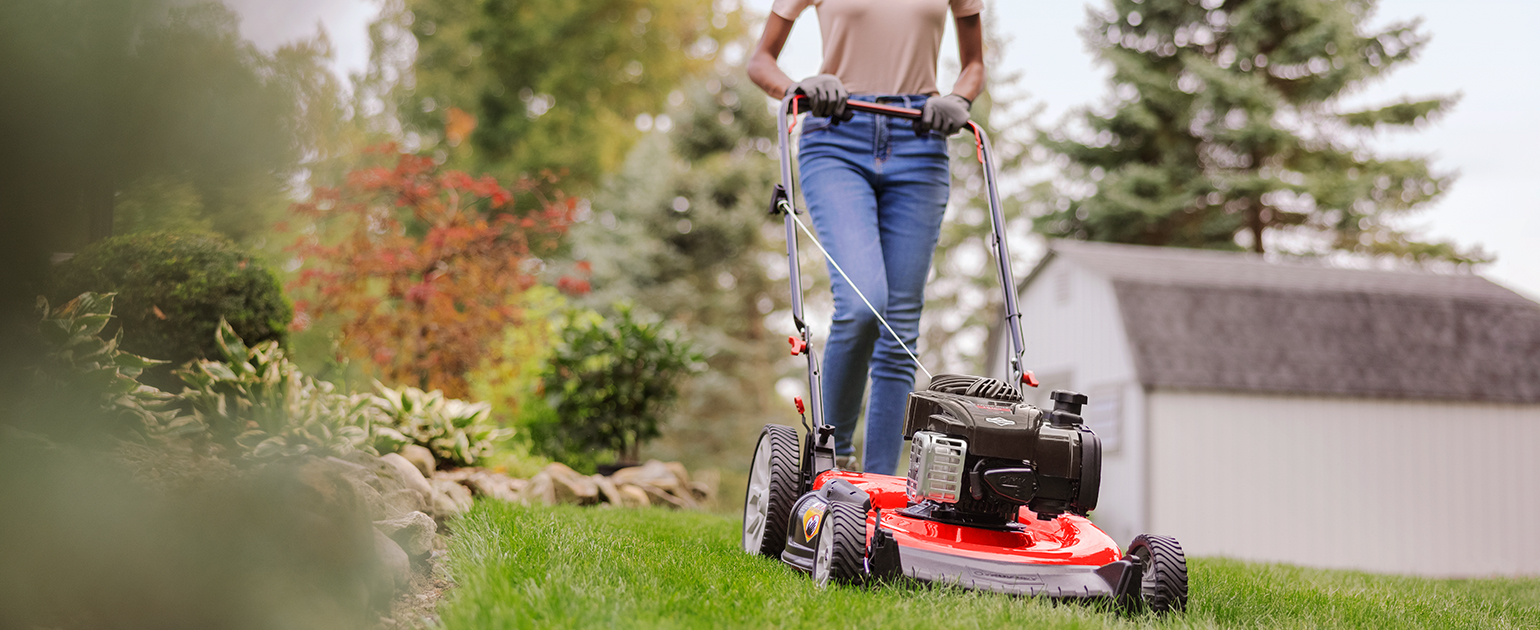woman cutting lawn with walk behind mower