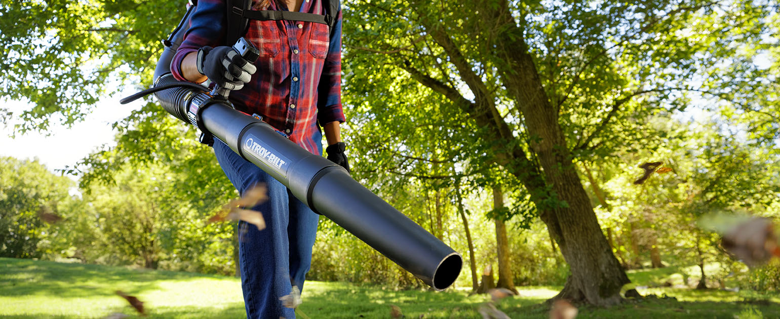 person using a leaf blower in grassy field