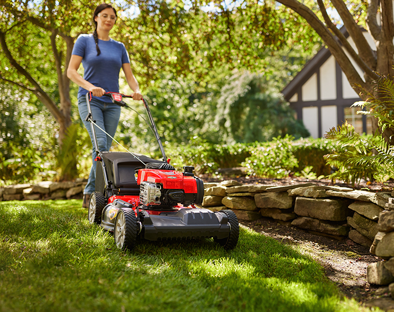 woman pushing push mower on grass