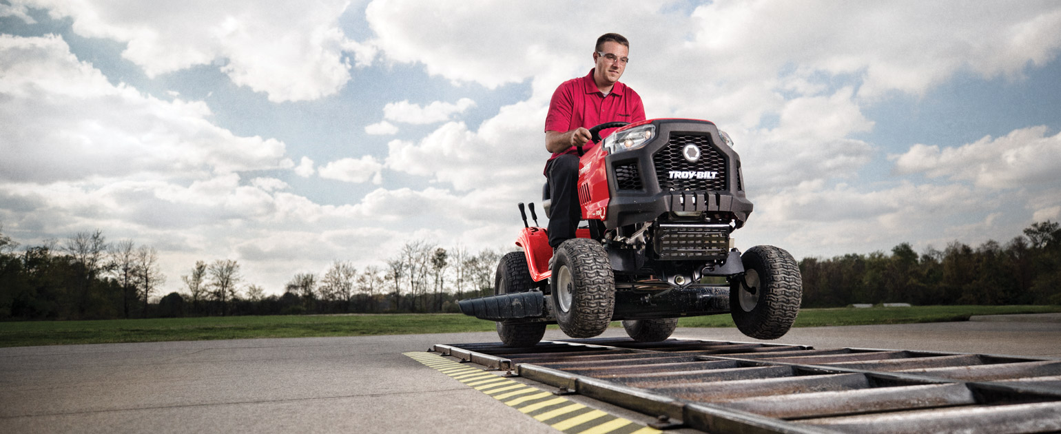 man riding riding lawn mower over concrete